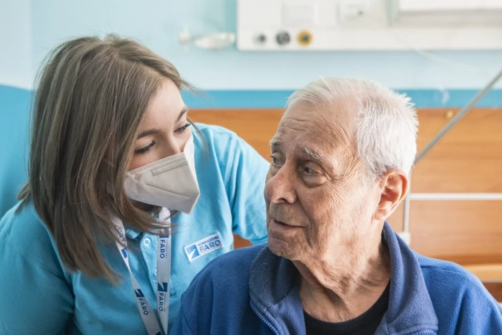A Fondazione FARO carer talking with an elderly patient